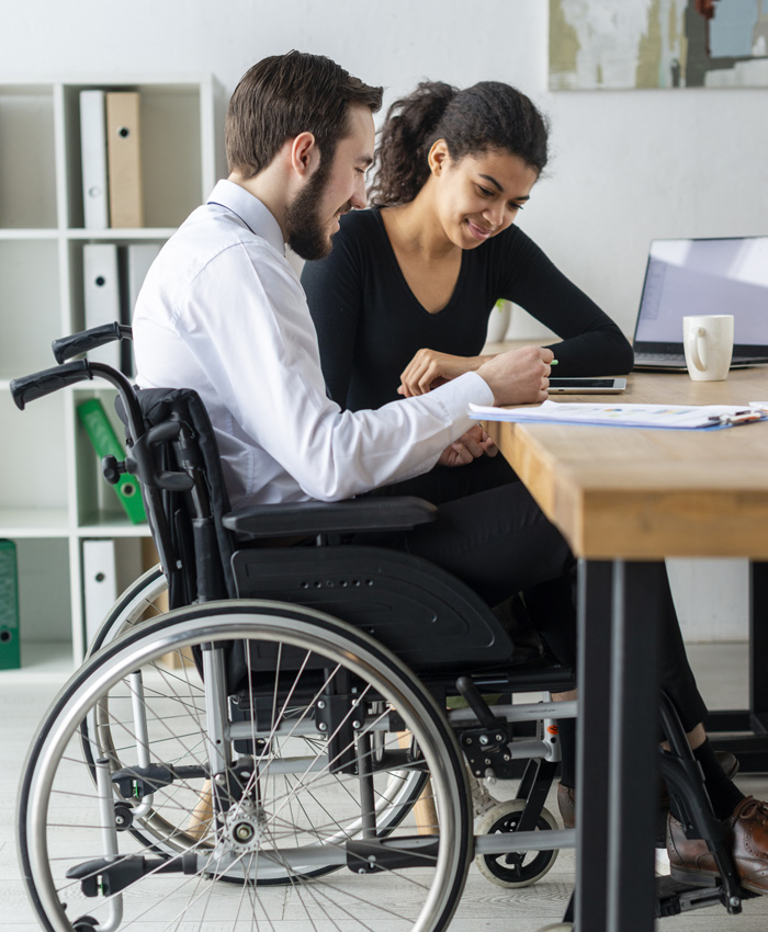 A caregiver assisting a person in a wheelchair with paperwork, fostering independence and engagement in a professional, supportive environment.